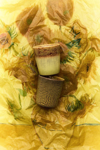 Two ceramic cups on a yellow fabric background with floral patterns