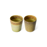 Two green ceramic cups with textured design on a white background