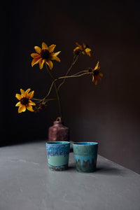 Two ceramic pots with sunflowers on a dark background