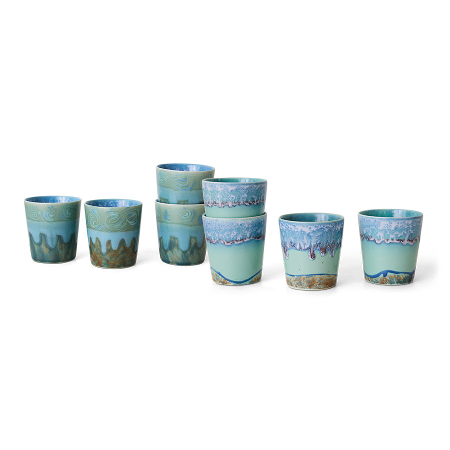 Set of ceramic cups with blue and green patterns on a white background