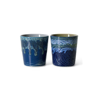 Two ceramic tumblers with wave design on a white background