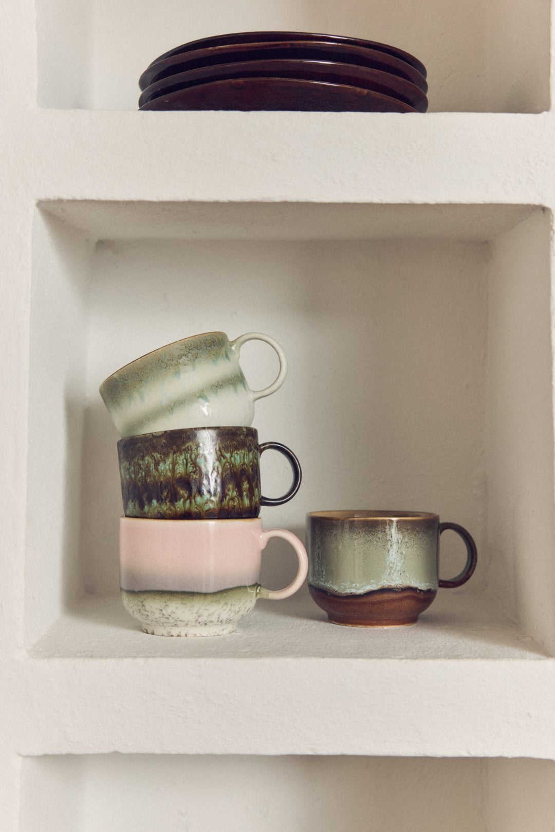 Set of ceramic mugs on a white shelf