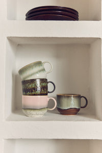Set of ceramic mugs on a white shelf