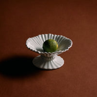 White decorative bowl with a green fruit on a brown background