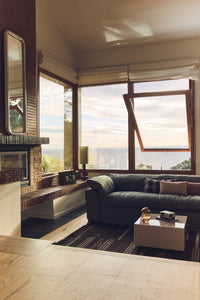 Modern living room with large windows, a fireplace, and a view of the ocean.