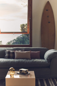 Living room with a gray sofa, coffee table, and surfboard on the wall.