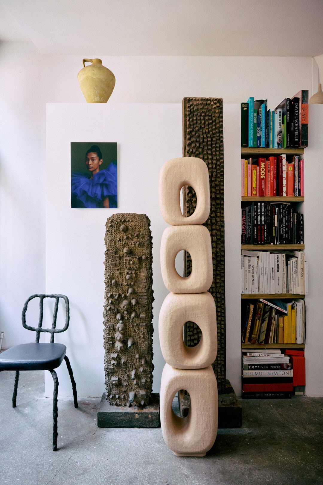 Room interior with sculptures, books, and a chair.