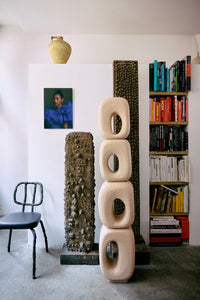 Room interior with sculptures, books, and a chair.