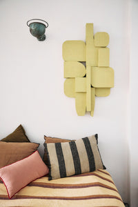 Decorative wall art above a bed with pillows and striped bedding.