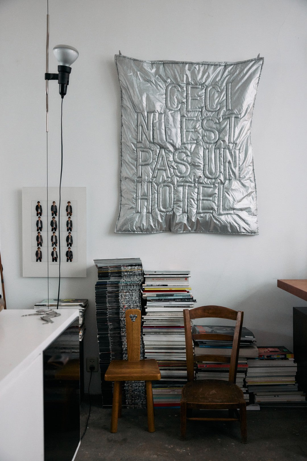 Room interior with a metallic color fabric wall hanging, books, and chairs.