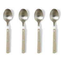 Set of four metal spoons with beige handles on a white background