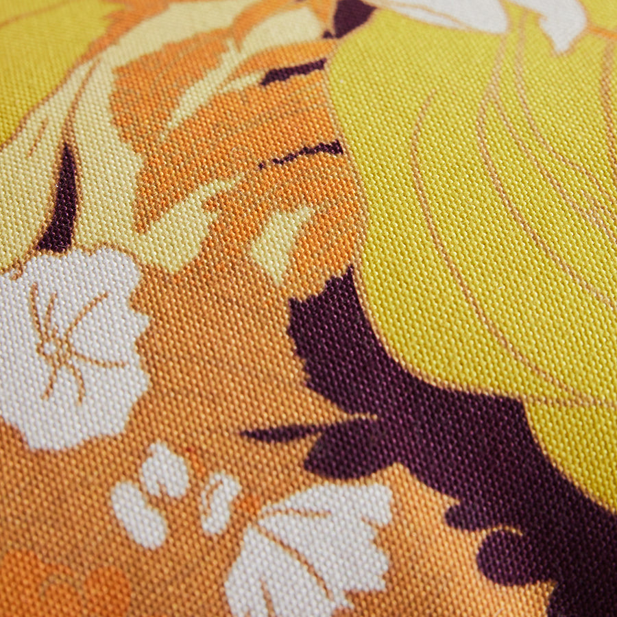 Close-up of a floral fabric with orange, yellow, and white flowers.