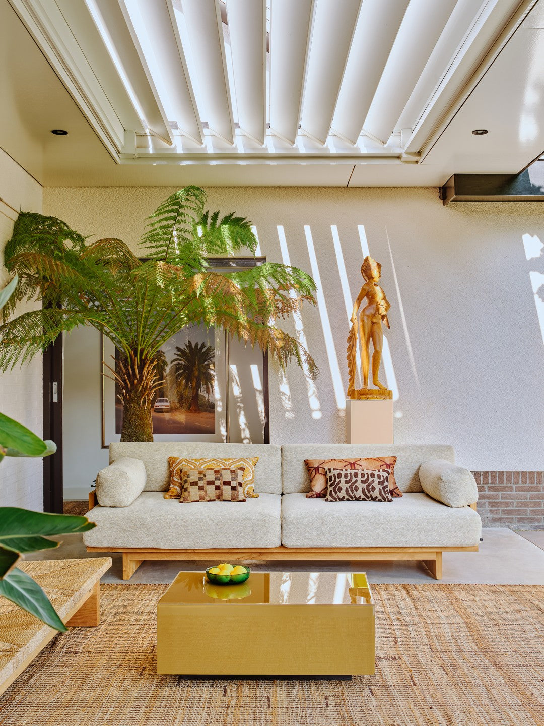 Modern living room with a white sofa, gold coffee table, and decorative elements.