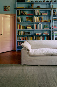 Living room with a bookshelf filled with books and a beige sofa.