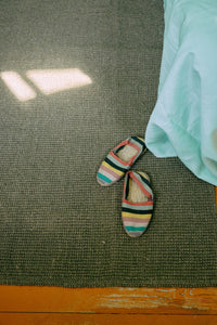 Pair of colorful slippers on a textured green floor.