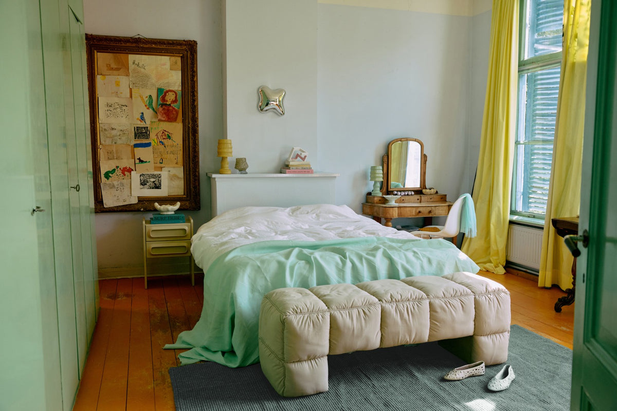 Bedroom with a bed, bench, and various items on a shelf.