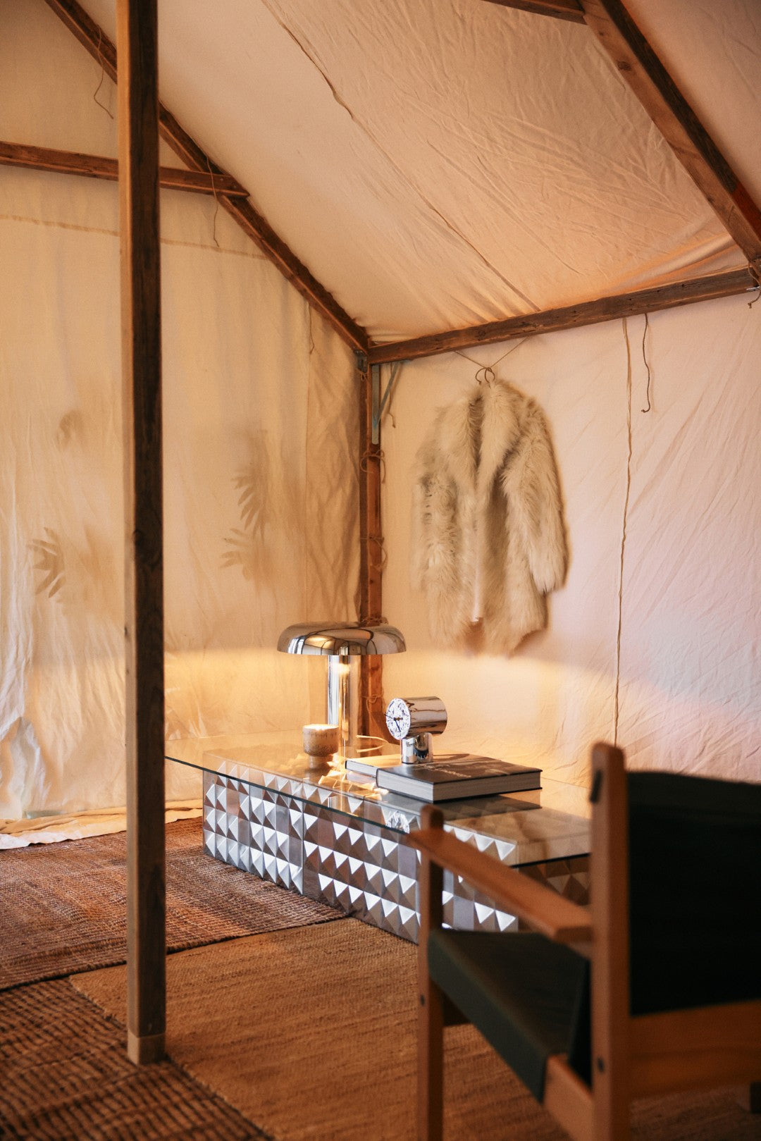 Interior of a tent with a glass table, chair, and decorative items.