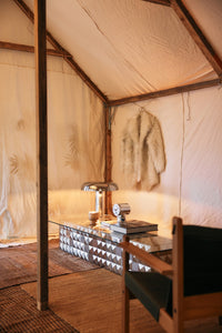Interior of a tent with a glass table, chair, and decorative items.