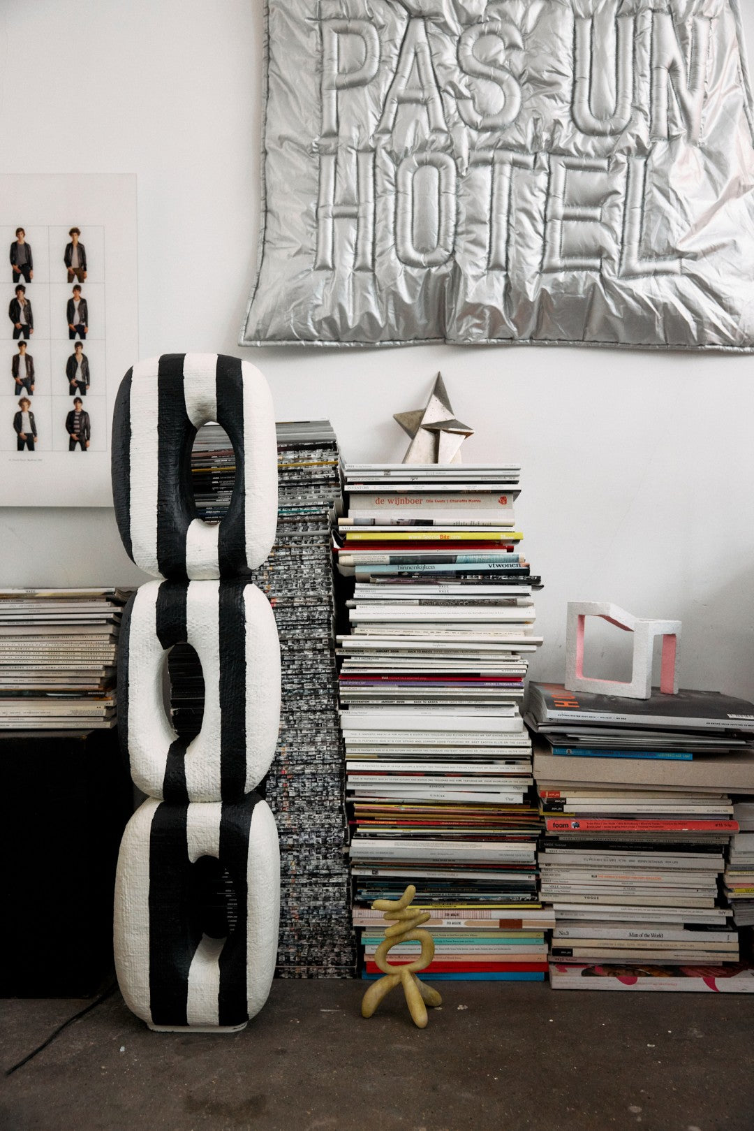 Black and white striped sculpture next to a stack of books with decorative items on a white wall.