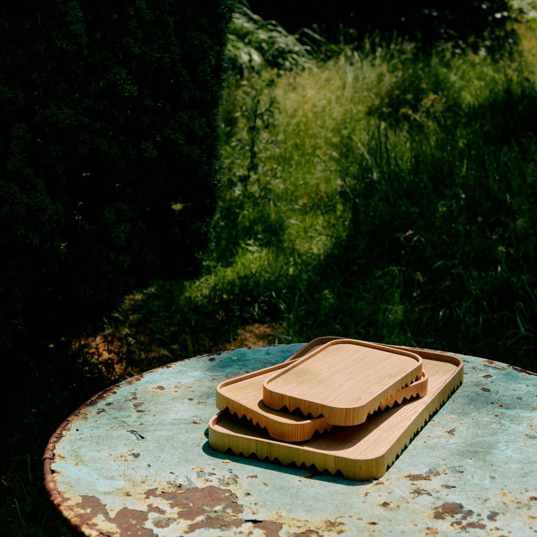 Three wooden cutting boards on a metal surface with a natural background