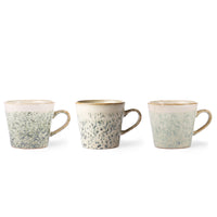 Three ceramic mugs with speckled design and brown rims on a white background