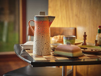 Ceramic pitcher on a checkered tablecloth with a blurred background