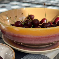 Cherries in a ceramic bowl on a checkered fabric background
