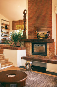 Modern living room with a brick fireplace, wooden shelves, and decorative items.