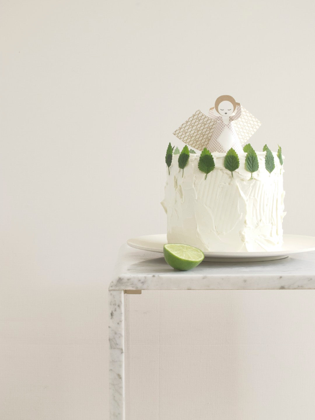 White cake with green decorations on a marble surface