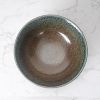 Ceramic bowl with a speckled glaze on a marble surface