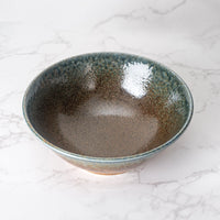 Ceramic bowl with speckled glaze on a marble surface