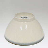 Beige ceramic bowl with a label on a white background