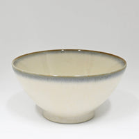 Ceramic bowl with a beige interior and brown rim on a white background