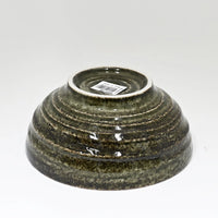 Green ceramic bowl with a label on a white background