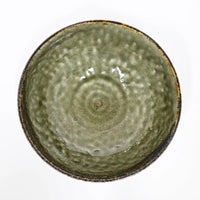 Green ceramic bowl with textured surface on a white background