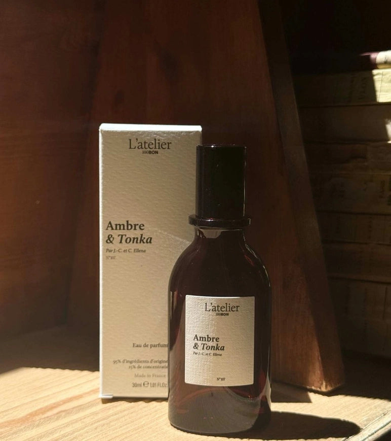 L'atelier Ambre & Tonka perfume bottle and packaging on a wooden surface.