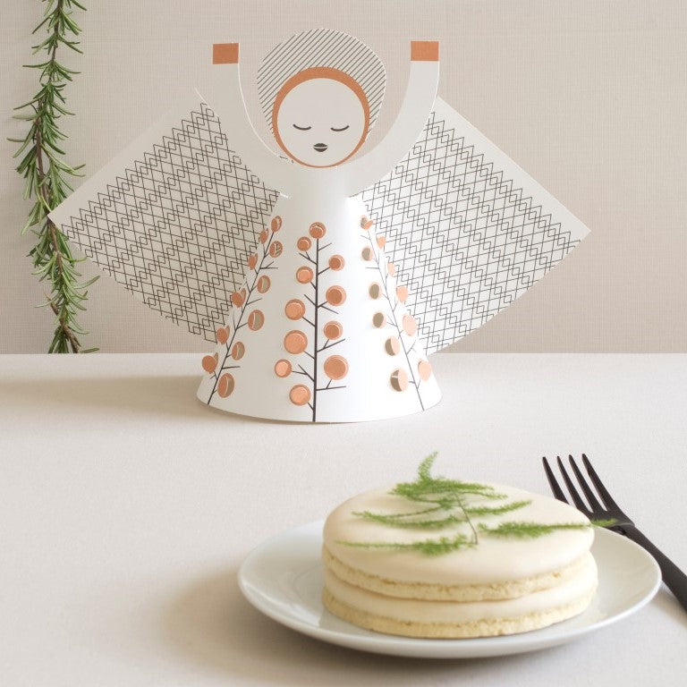 Small cake on a plate with a decorative angel figurine in the background