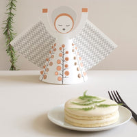 Small cake on a plate with a decorative angel figurine in the background