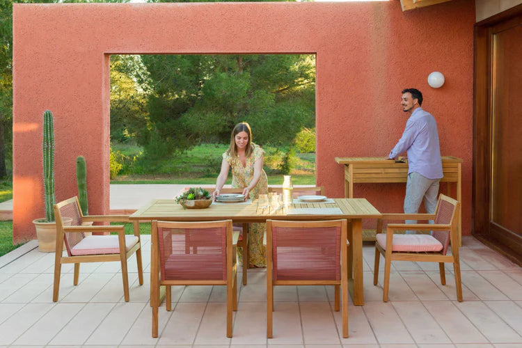 Two people sitting at an outdoor dining table with chairs on a patio.