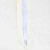 Close-up of a white zipper on a light beige background