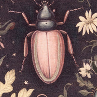 Embroidered pink beetle on a dark fabric background with floral patterns