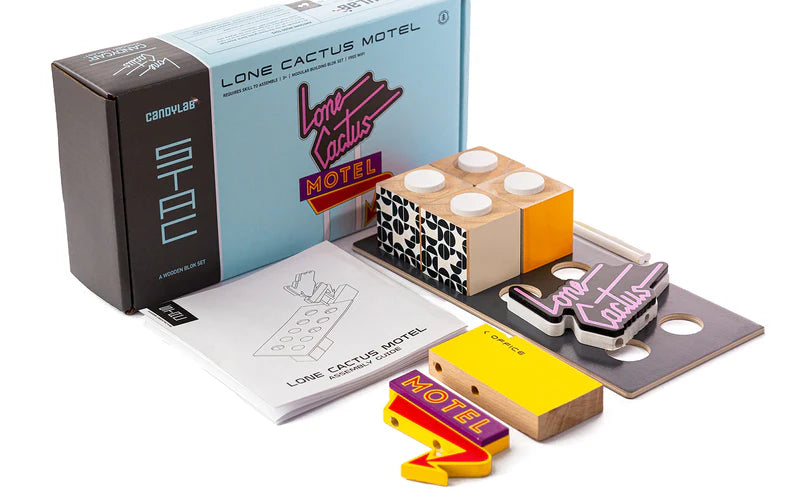Collection of 'Lone Cactus Motel' themed items including a box, stickers, and a notebook on a white background.
