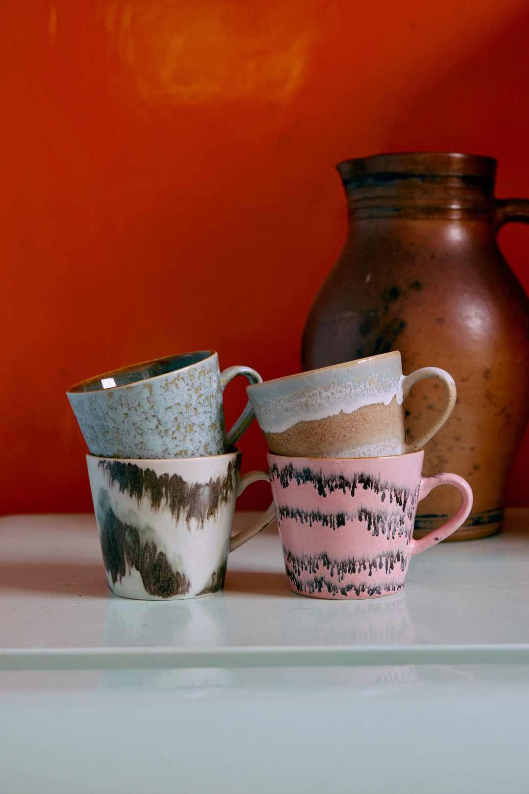 4 mugs with ears in different colors on an orange background