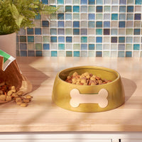 Dog food bowl with bone design on a wooden surface, filled with kibble.