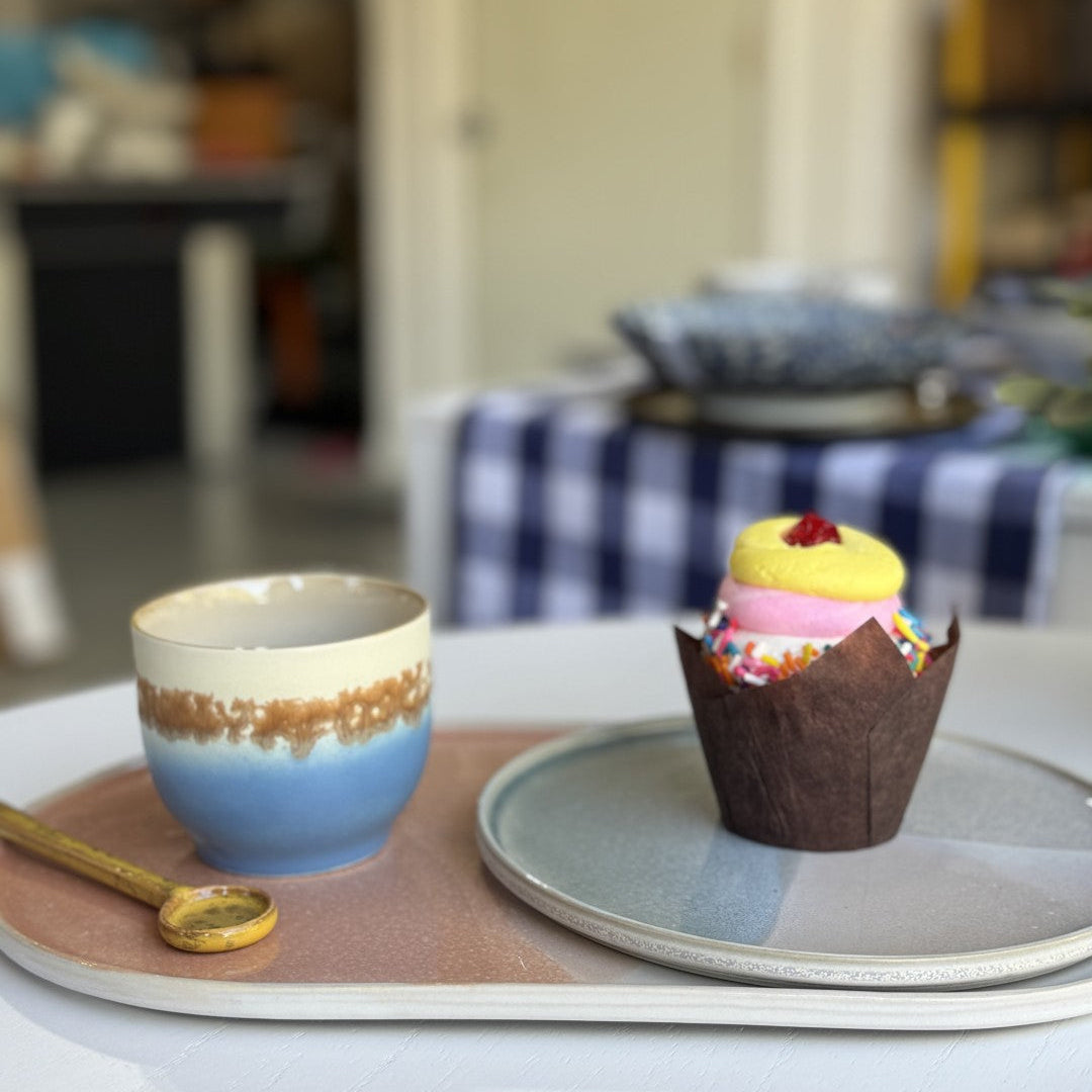 Cupcake and ceramic cup on a tray with a blurred background