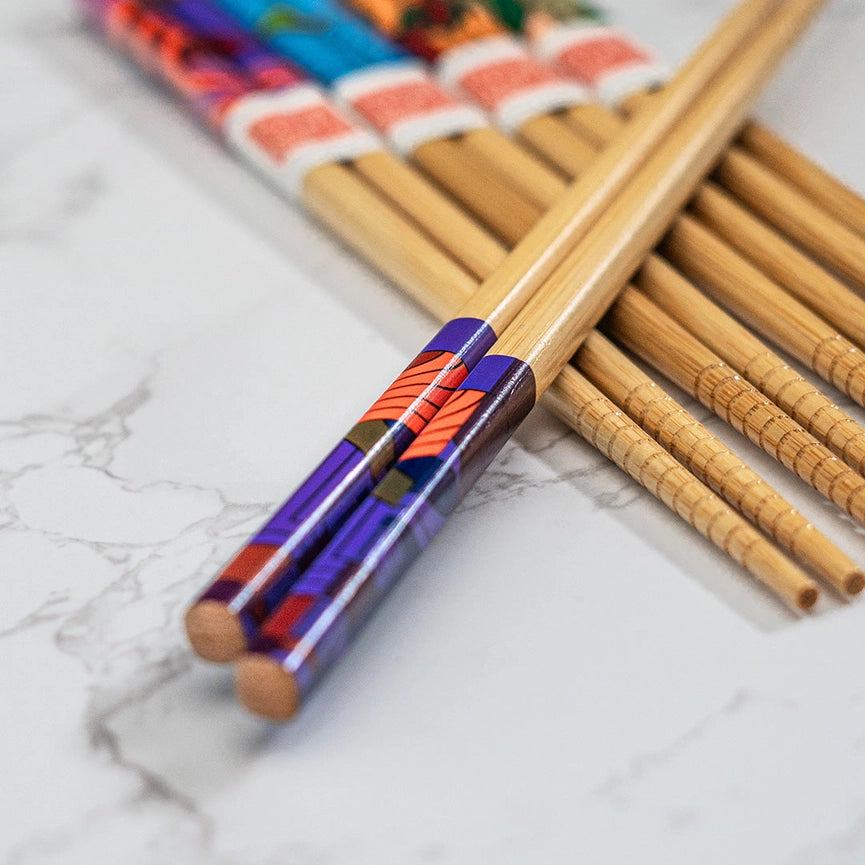 Pair of wooden chopsticks with colorful handles on a marble surface