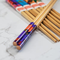 Pair of wooden chopsticks with colorful handles on a marble surface