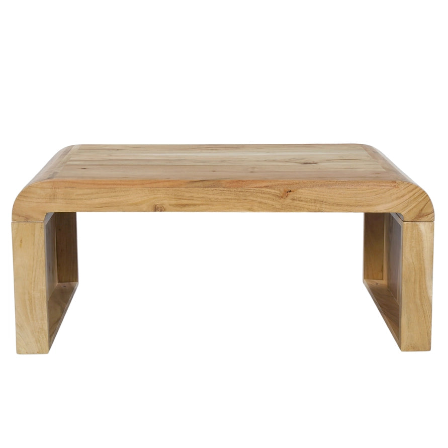 A low wooden table with a natural light oak finish, featuring a thick rectangular top with rounded corners and integrated block-style legs, shown against a plain white background.