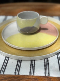 dinner and side plate with coffee cup in pastel colors on striped cloth