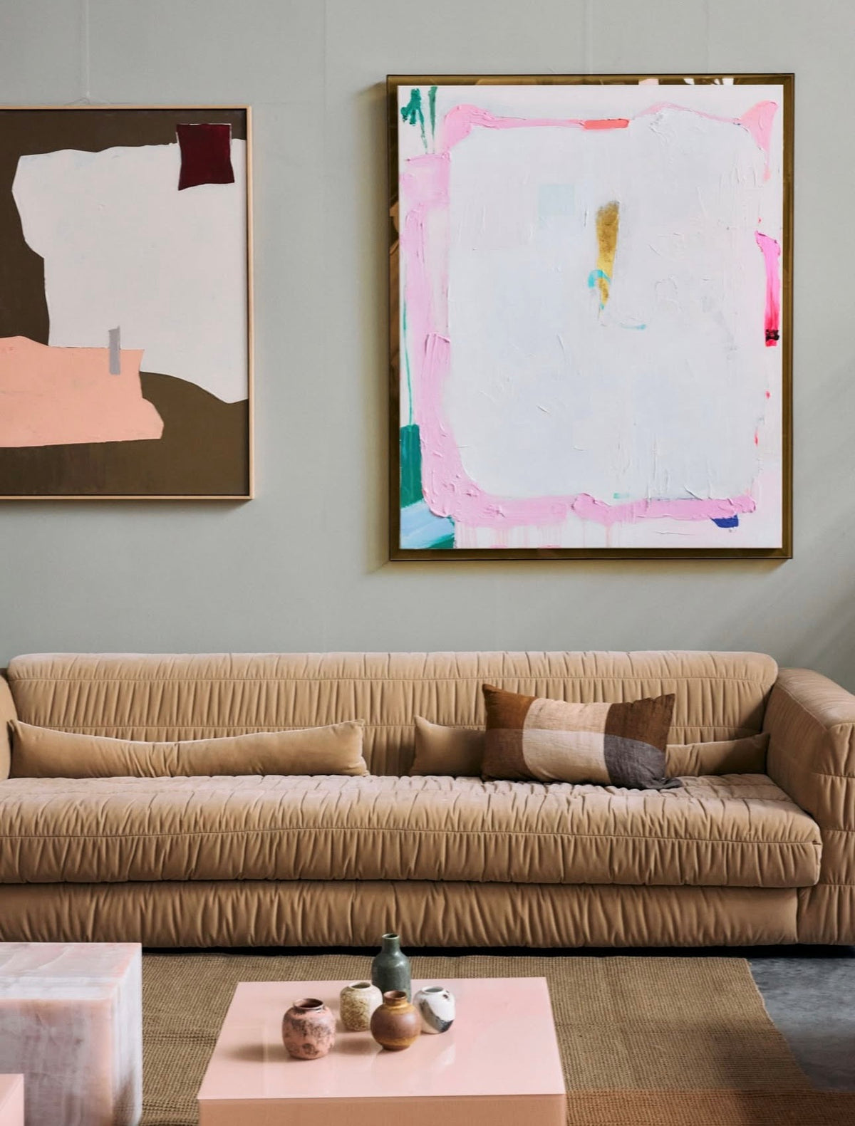 caramel velvet sofa with two abstract paintings an a grey wall